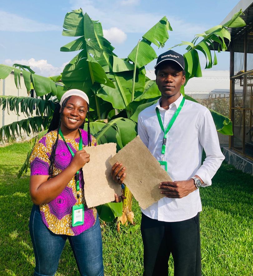 Blessing Ekwere and Dave Olaniyan holding banana-stem paper beside banana plants